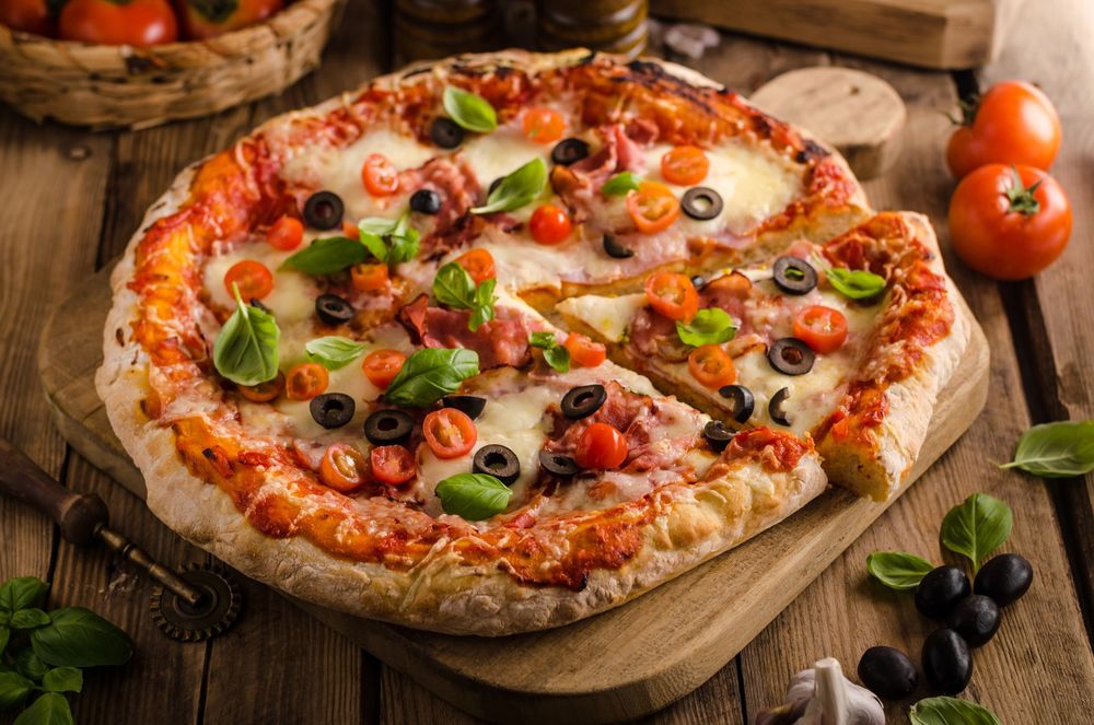 Обои Аппетитная пицца на деревянной доске, рядом оливки, чеснок и листья шпината на рабочий стол