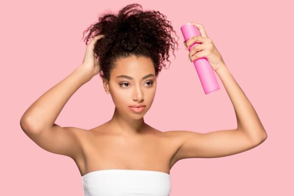 красивая африканская американская девушка с бутылкой лака для волос, изолированная на розовый - Фото, изображение